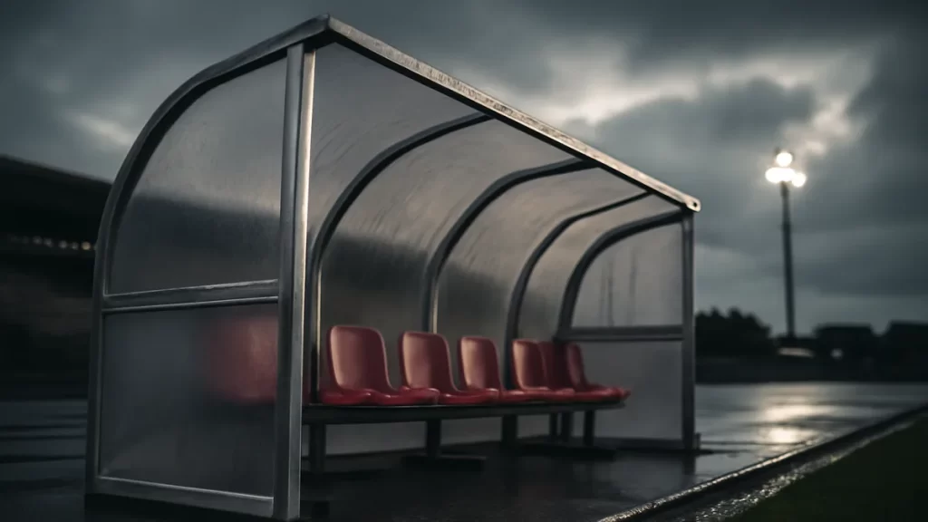 Weather protection for a club: benches, covers and shelters explained Empty covered bench and folded portable shelter beside wet sideline.